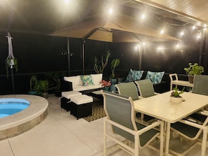An outdoor patio with a pool, seating area, and potted plants.