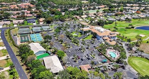 An aerial view of a residential area with a golf course, a swimming pool, and a large building with a parking lot.