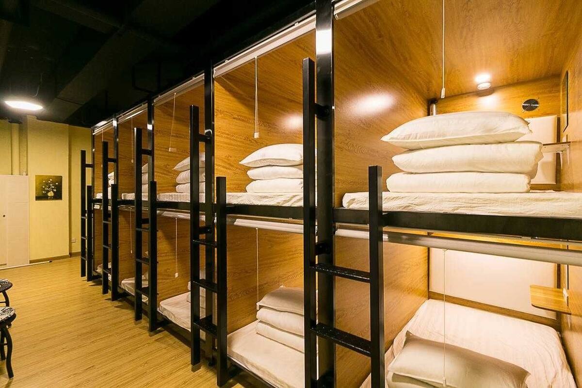 Bunk beds with wooden frames and white bedding in a room with wooden flooring and a small table.