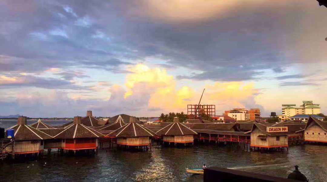 Una propiedad frente al mar con bungalows sobre el agua, un muelle y un edificio con la leyenda 'DRAGON INN'.