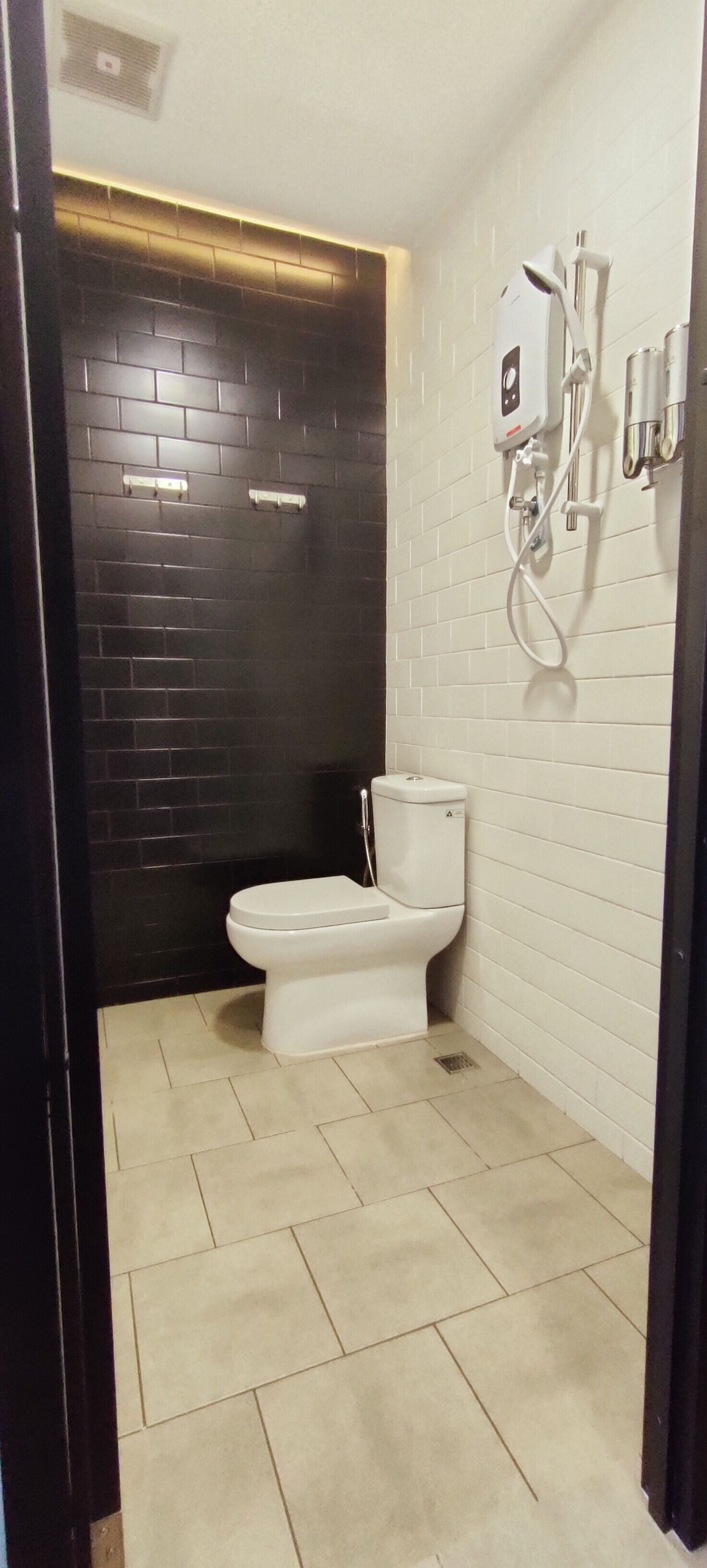 A bathroom with a toilet, a shower, and a hand dryer.