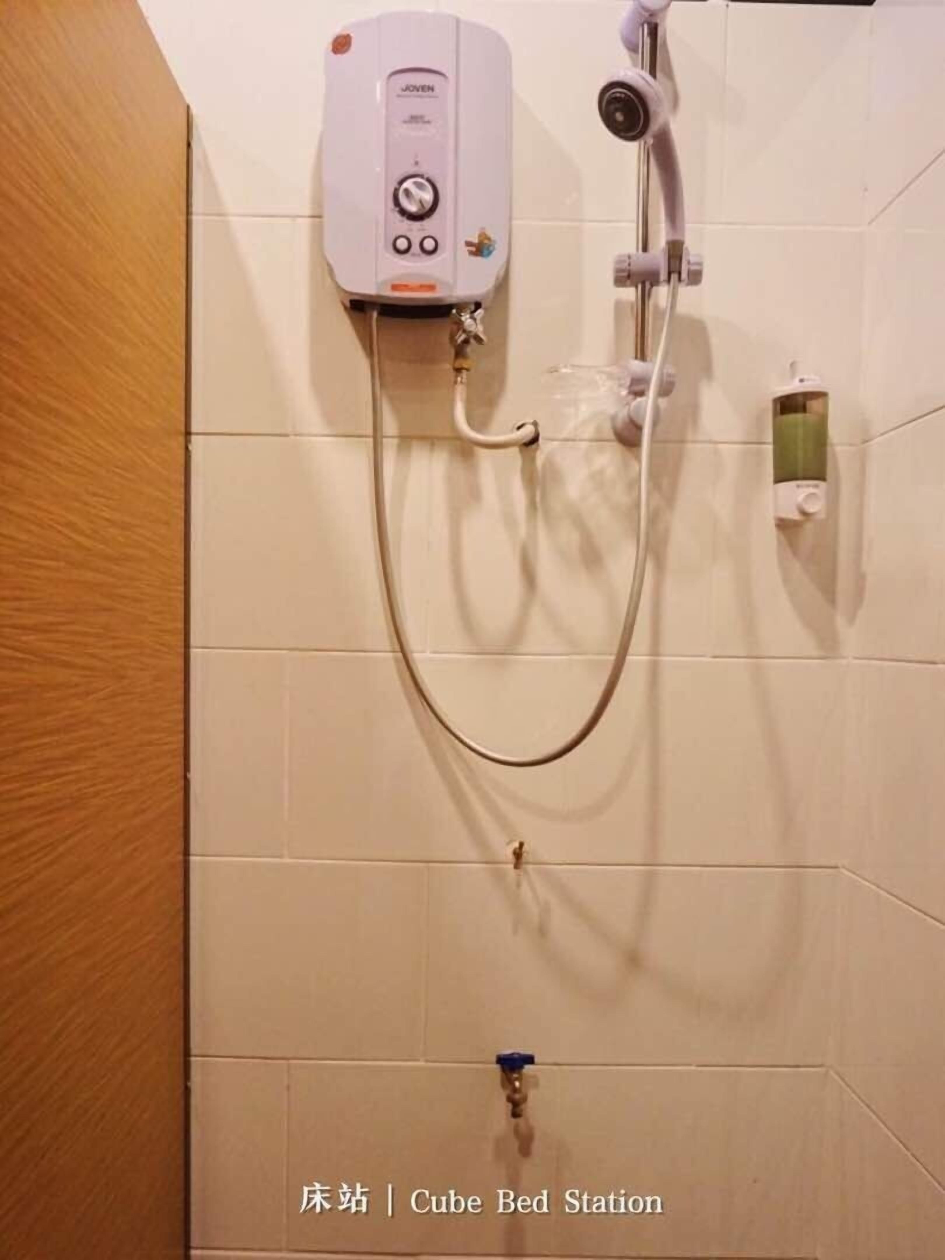 A shower with a control panel, a handheld showerhead, and a handheld faucet.