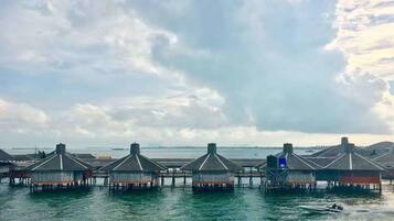 Overwater bungalows with a view of the sea and a distant shoreline.