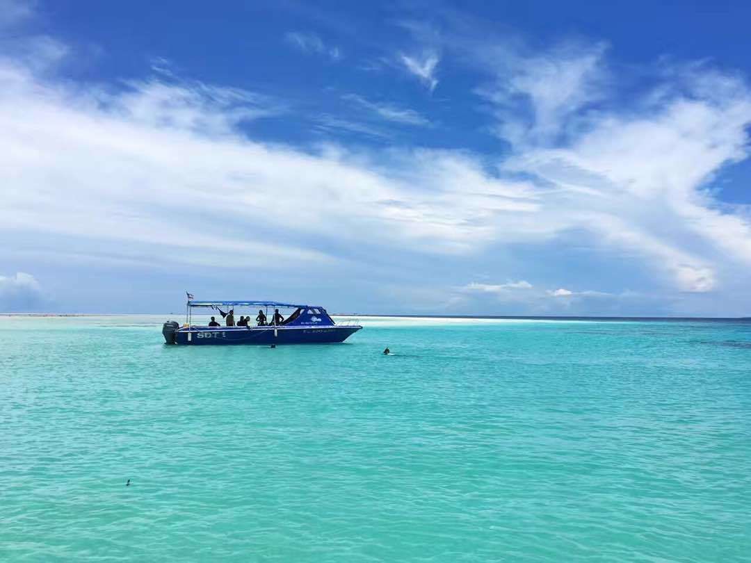 A boat on turquoise water with a clear sky.