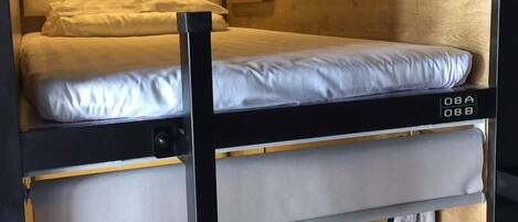 A bunk bed with a headboard, a mirror, and a wall-mounted light fixture.