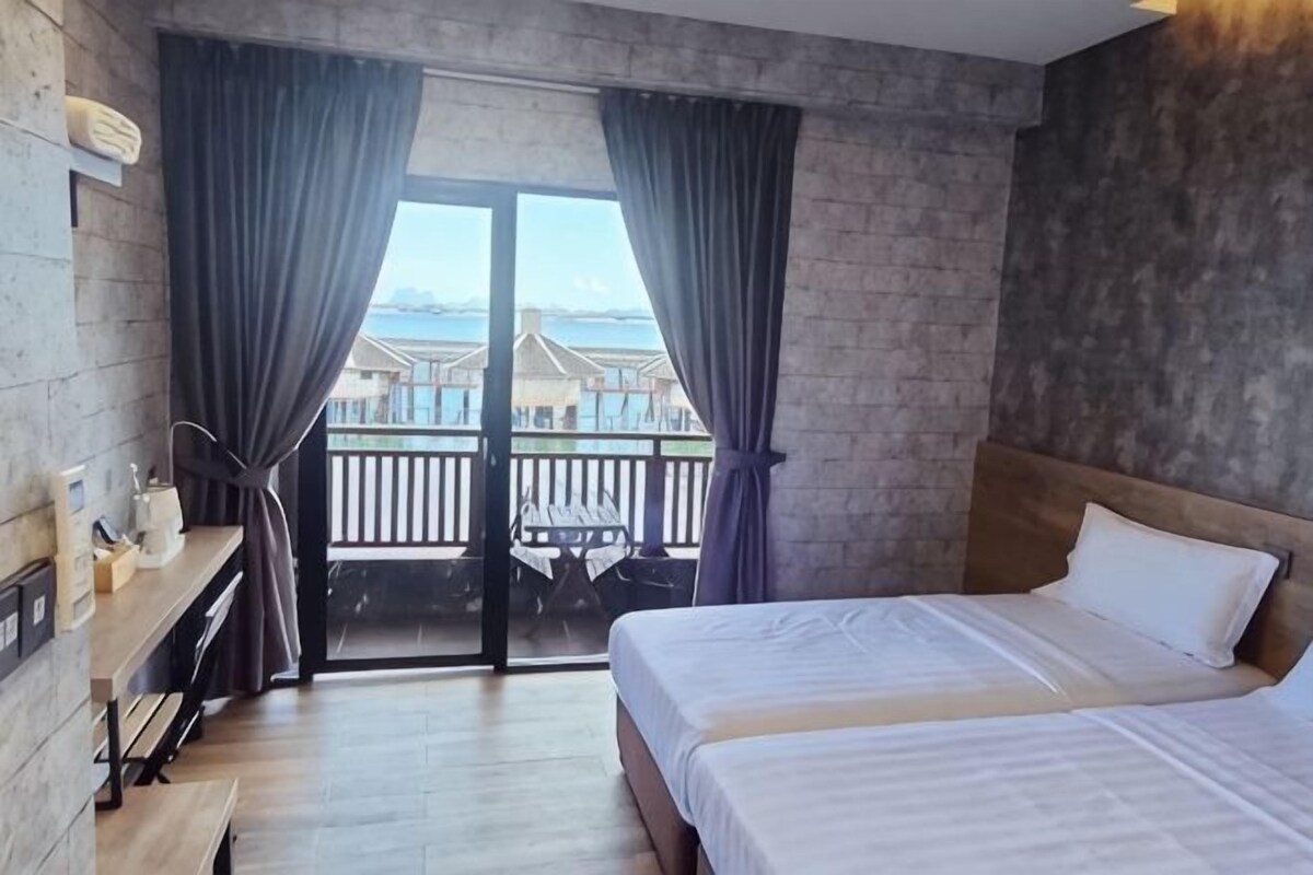 A hotel room with a bed, a desk, and a view of a balcony.