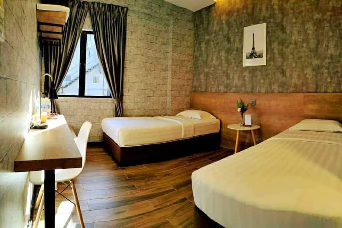 A hotel room with two beds, a desk, and a small table.
