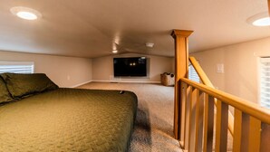 A bedroom with a bed, a TV, and a staircase.