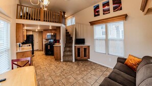 A spacious living area with a kitchen, a staircase to an upper level, and a dining area.