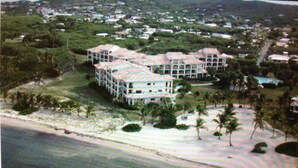 Un hôtel situé en bord de mer, composé de plusieurs bâtiments, agrémenté de palmiers et donnant sur une plage.