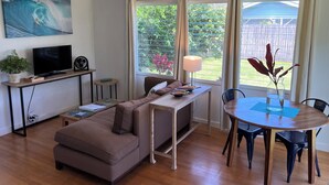 A cozy living room with a sofa, TV, and dining table. - Great Location, Clean, Beachy 1BR Cottage (Haiku-Pauwela)