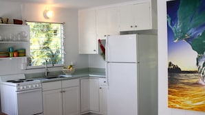 A kitchen with white cabinets, a stove, a sink, and a refrigerator. - Great Location, Clean, Beachy 1BR Cottage (Haiku-Pauwela)