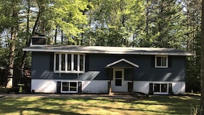 A two-story house with a front porch, surrounded by trees.