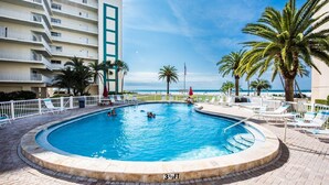 A swimming pool with a 3½ ft depth, surrounded by lounge chairs and palm trees, with a view of the ocean and a building in the background. - Great rates for September! SIESTA KEY GULF 2 bed 2 bath condo Jamaica Royale 104 (Sarasota)