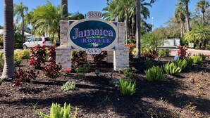 A sign for Jamaica Royale with the number 5830, surrounded by landscaped gardens and palm trees. - Great rates for September! SIESTA KEY GULF 2 bed 2 bath condo Jamaica Royale 104 (Sarasota)