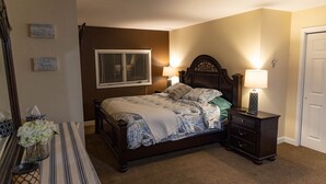 A bedroom with a bed, bedside lamps, a nightstand, a window with blinds, and wall decorations. - Luxury Living On The Lake (La Porte)