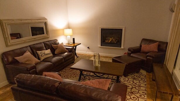 A cozy living room with a brown leather sofa set, a coffee table, and a fireplace. - Luxury Living On The Lake (La Porte)