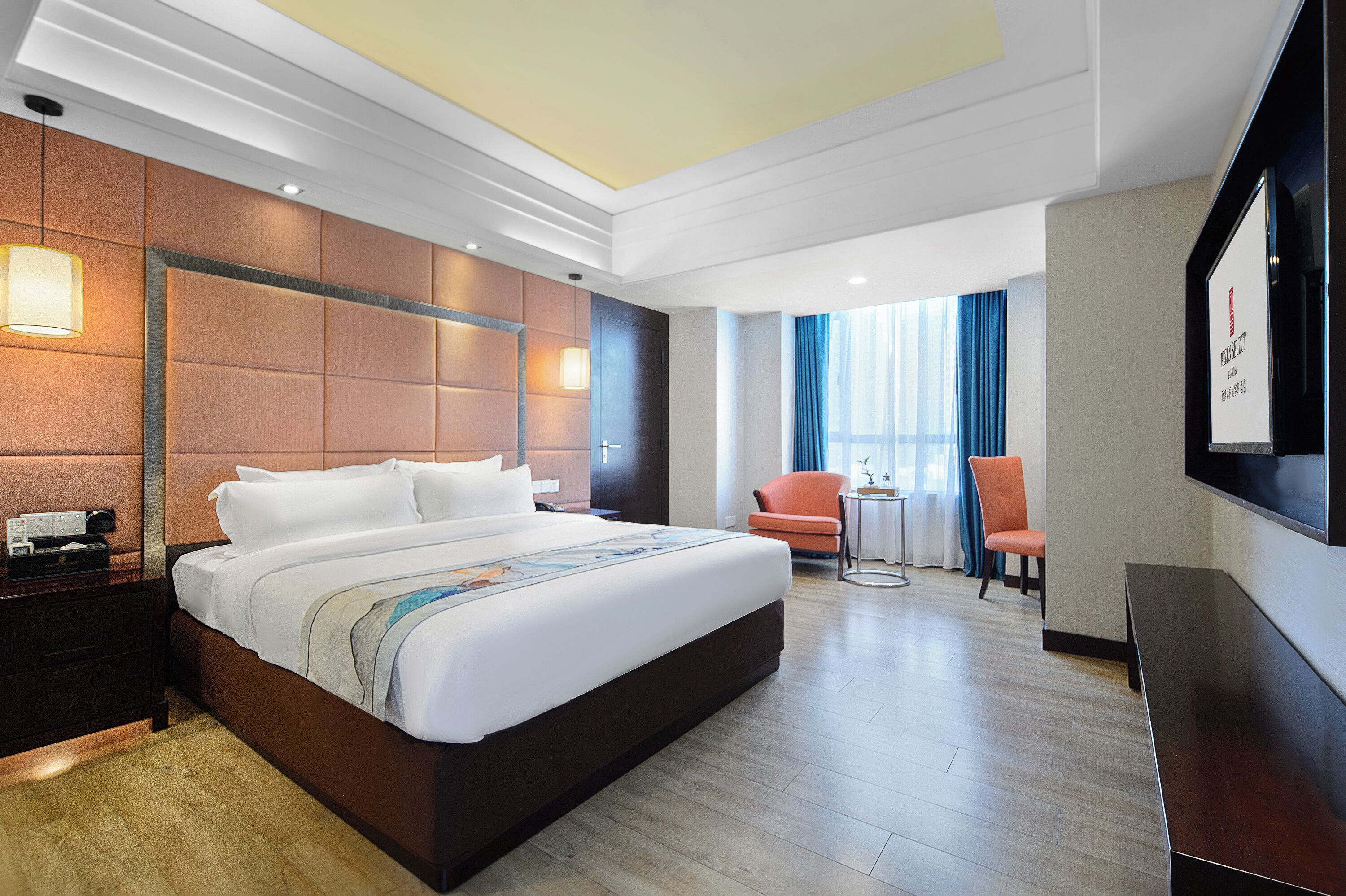 A hotel room with a large bed, a desk, a chair, and a TV on the wall.