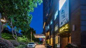 Ein Hotel mit rotem Teppich, Autos vor der Fassade und guter Beleuchtung.