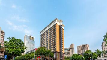 A tall hotel with a modern design, featuring a prominent corner entrance and multiple floors.