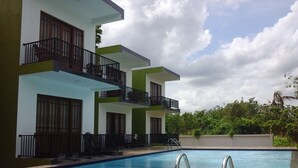 Um edifício moderno com piscina, varandas e céu claro.