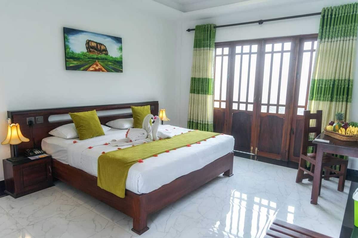 Una habitación de hotel con una cama grande, una mesita de noche, un escritorio con una cesta de fruta y un cuadro en la pared.