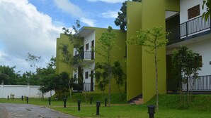 Um edifício moderno com telhado plano, várias varandas e esquema de cores verde e branco.