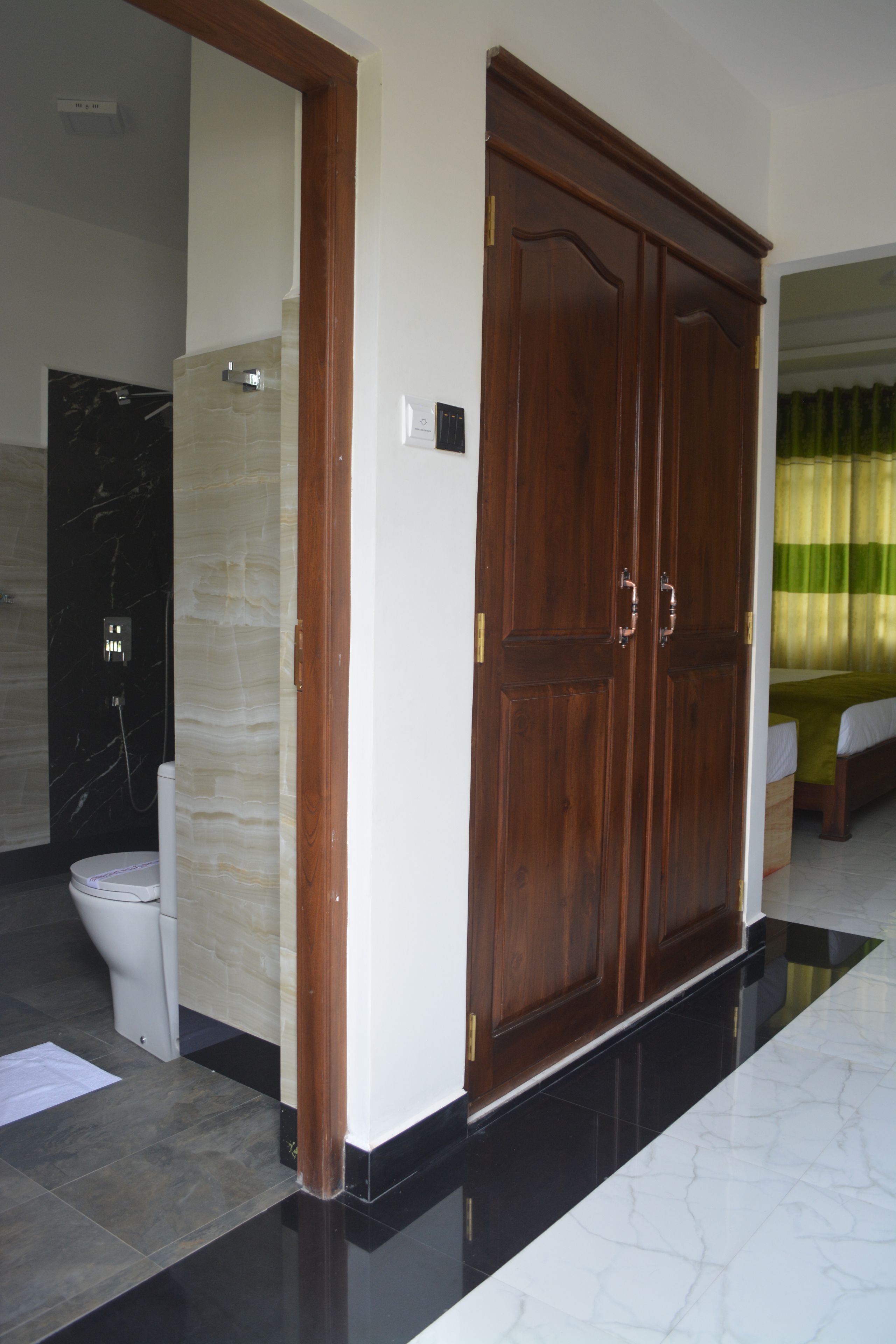 A bathroom with a marble wall, a toilet, and a wooden wardrobe.