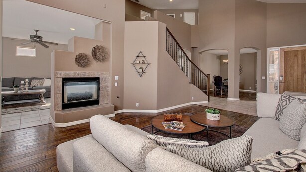 A spacious living room with a fireplace, a staircase, and a dining area. - Beautiful Golf Course with Pool &  Mountain views! (Glendale)