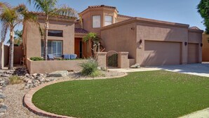 A two-story house with a well-maintained lawn, palm trees, and a gated driveway. - Beautiful Golf Course with Pool &  Mountain views! (Glendale)