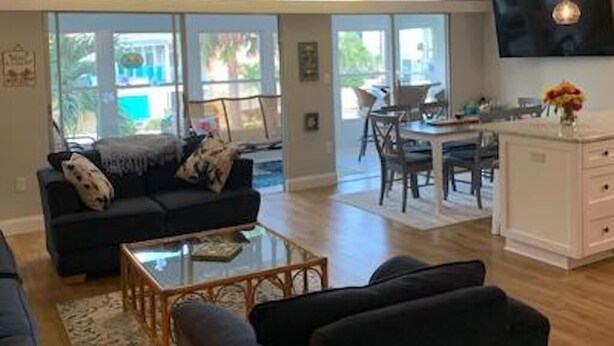 A modern living room with a sofa, coffee table, and TV. There is a dining area with a table and chairs. - Newly Renovated kitchen, guest and master bathrooms (Clearwater)