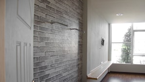 Een kamer met een bakstenen muur, een raam met uitzicht en een houten bank.