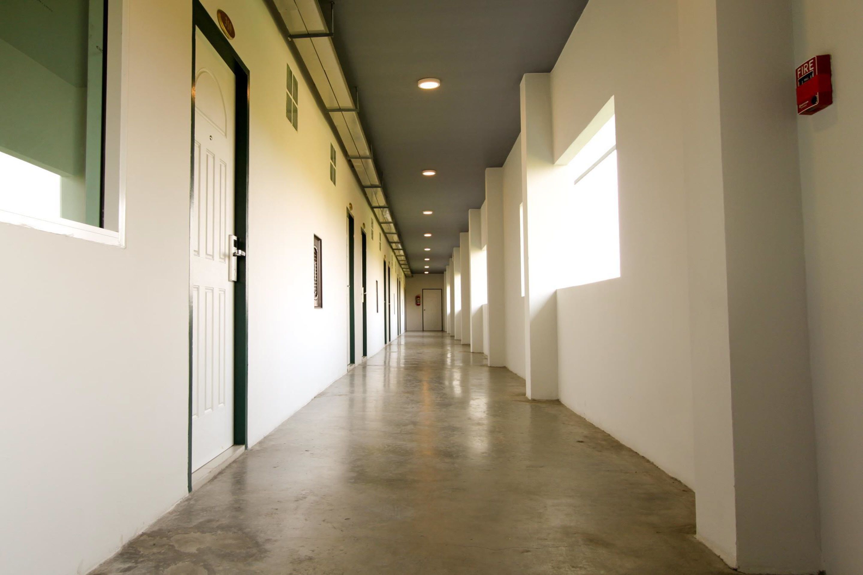 A long, narrow hallway with doors on one side and windows on the other.