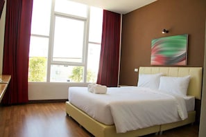 A hotel room with a bed, a desk, and a window with curtains.