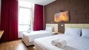 Een hotelkamer met twee bedden, rode gordijnen, een groot raam en een schilderij aan de muur.