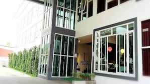 Een modern gebouw met grote ramen, een zichtbare trap en een bord dat de begane grond aangeeft.
