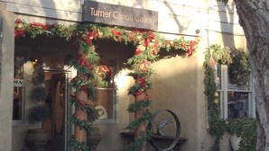 A building with a sign reading "Turner Carroll Gallery" and a decorated entrance with greenery and ornaments.