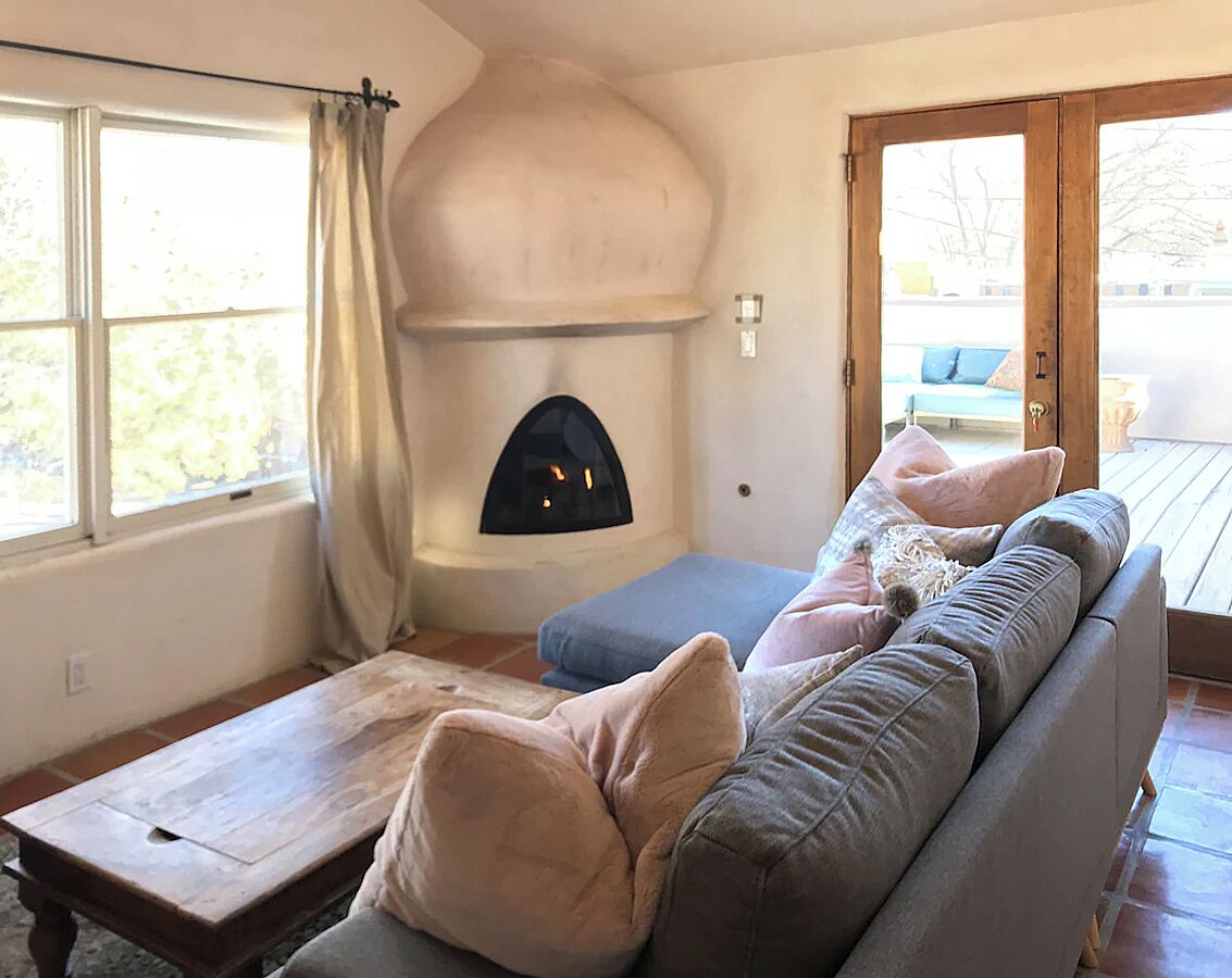 Ein gemütliches Wohnzimmer mit Kamin, einer Couch und einem Fenster.