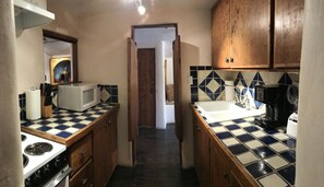 A narrow kitchen with a microwave, stove, sink, and coffee maker. - Canyon Road Historic Location for Art & Dining, Walk to Everything! (Santa Fe)