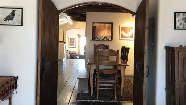 A wooden hallway with a bench, a table, and a chair. There are two doors on either side of the hallway.