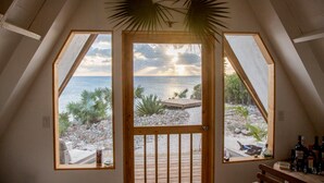 Ett rum med utsikt över havet genom ett stort, triangulärt fönster.