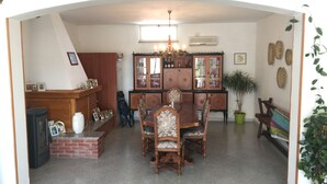 Un comedor con una mesa y sillas de madera, una chimenea de ladrillo y un armario grande con puertas de cristal.