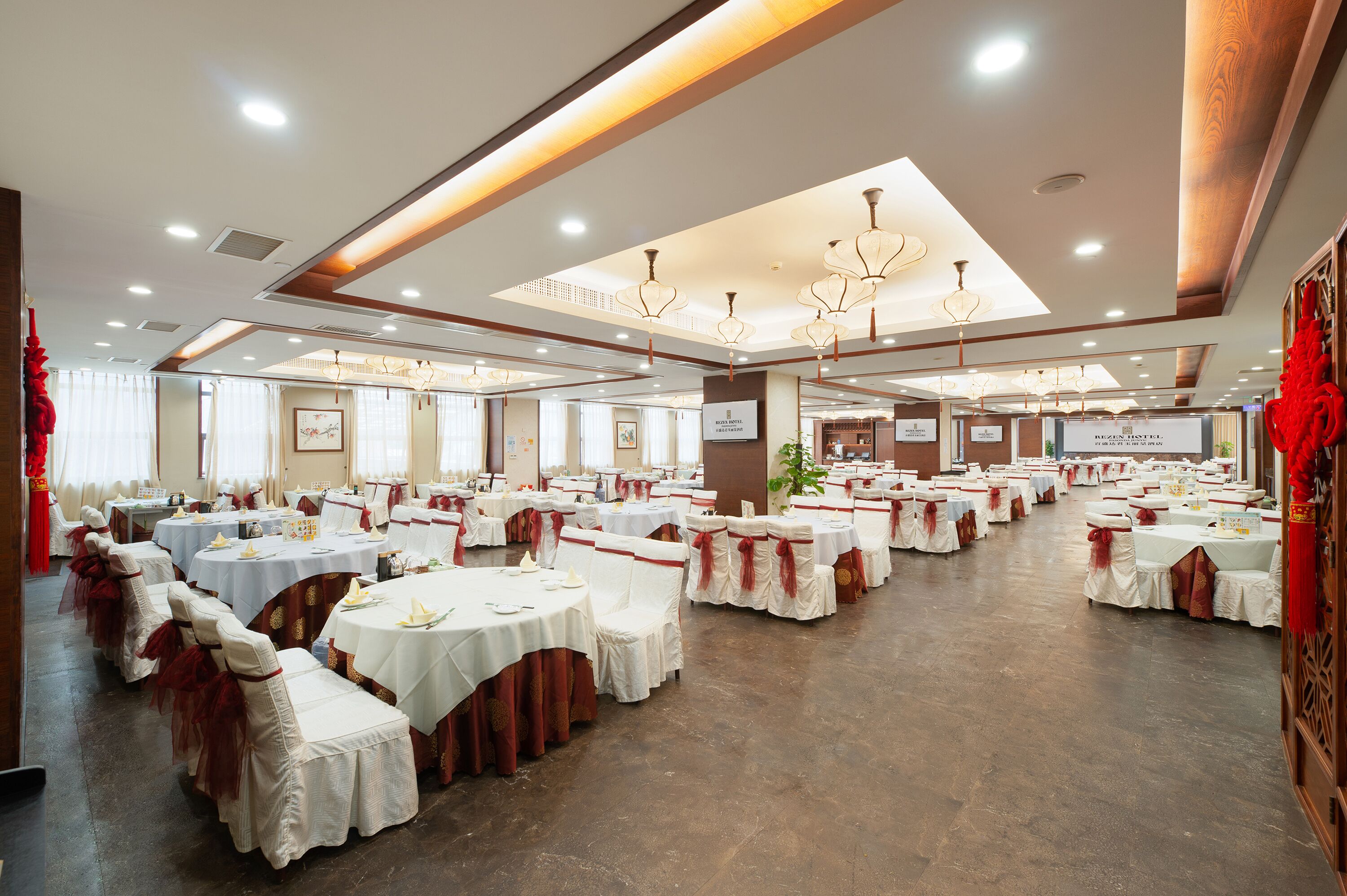A banquet hall with round tables and chairs, a chandelier, and a sign for 'Hotel Restaurant'.