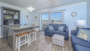 Un espacio habitable compacto con kitchenette, comedor, sofá y un amplio ventanal con vistas.