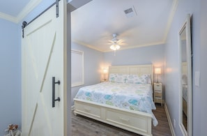 Une chambre à coucher avec un lit, un ventilateur de plafond, des tables de chevet et une petite table de nuit.