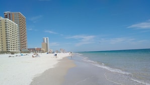 Una playa con una orilla arenosa, un muelle a lo lejos y varios edificios a lo largo de la costa.