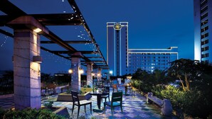 An outdoor patio area with seating and a view of a hotel building. - Regal Palace Hotel  (Dongguan)