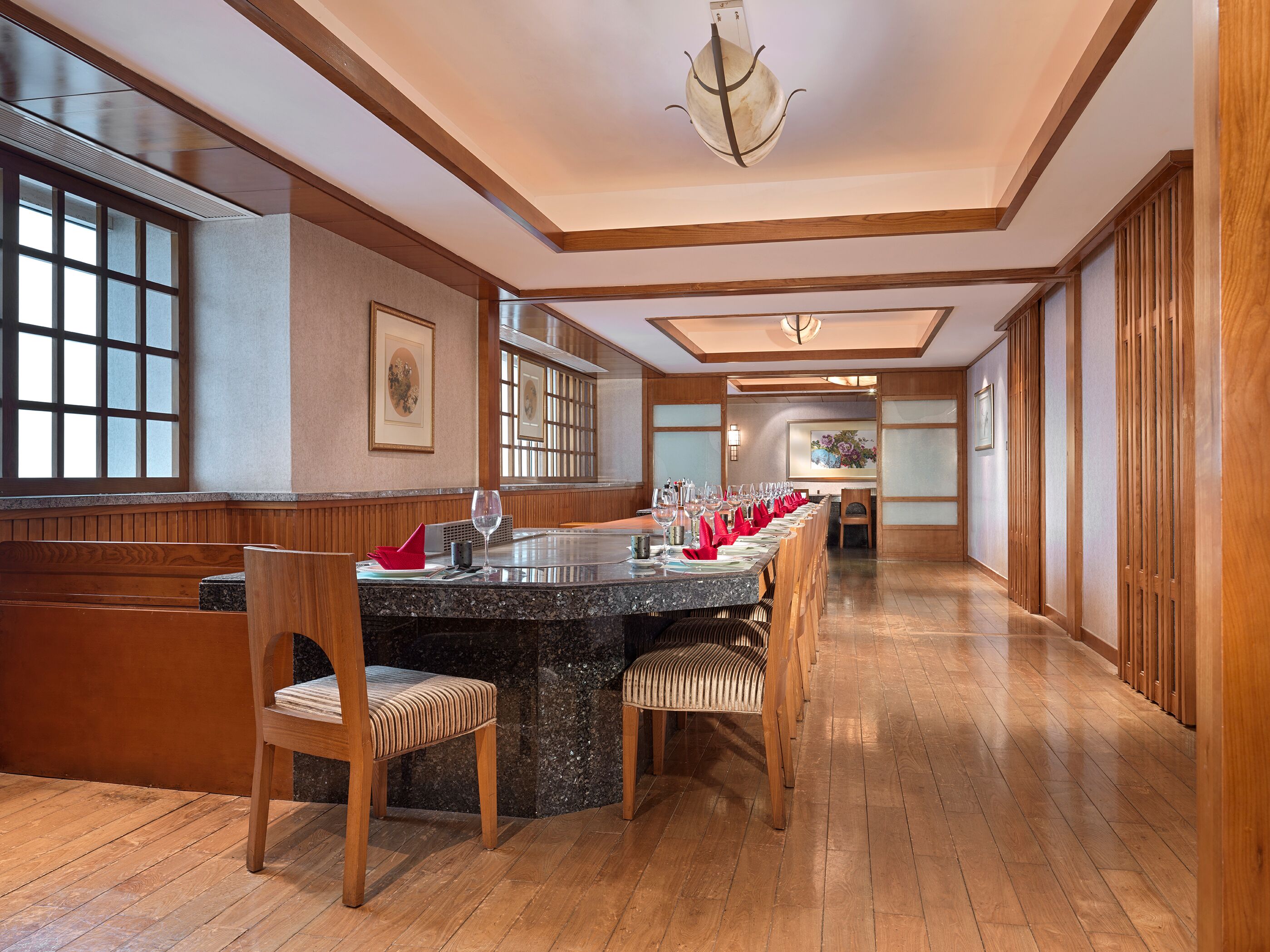 A long dining table with chairs, a chandelier, wooden paneling, and artwork on the walls.