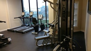 A gym with treadmills, elliptical machines, and weightlifting equipment. - BEAUTIFUL BEACHSIDE CONDO with POOLS, HOTTUB, TENNIS, PICKLEBALL & VOLLEYBALL! (Gulf Shores)