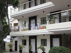 Un immeuble résidentiel à plusieurs étages, doté de balcons, de plantes en pot et d’une architecture moderne.